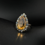 Bague d'exception pour femme en citrine jaune taille poire et topazes bleues sur monture en argent 925 texturé sur satin blanc