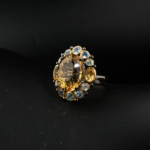 Bague pour femme en citrine jaune ovale naturelle et topazes bleues scintillantes en argent 925 sur tissu blanc.