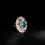 Bague cocktail royale pour femme en argent 925 avec topaze bleue, citrine, améthyste, grenat et péridot sur satin blanc.