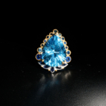 Bague royale pour femme en argent 925 avec topaze bleue poire et halo de saphirs bleus sur satin blanc.