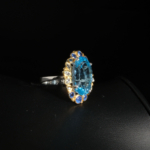 Bague royale pour femme en argent 925 avec topaze bleue ovale et halo de saphirs bleus sur satin blanc.