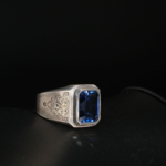 Bague chevalière pour homme en argent 925 gravé avec saphir bleu naturel taille baguette sur satin blanc.