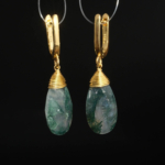Boucles d'oreilles pendantes en agate mousse naturelle facettée et argent 925 doré sur satin blanc