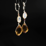 Boucles d'oreilles pendantes pour femme en citrine jaune taille poire, pierre de lune et améthyste en argent 925 sur satin blanc.
