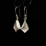 Boucles d'oreilles pendantes géométriques pour femme en quartz rutilé noir naturel et argent 925 sur tissu blanc.