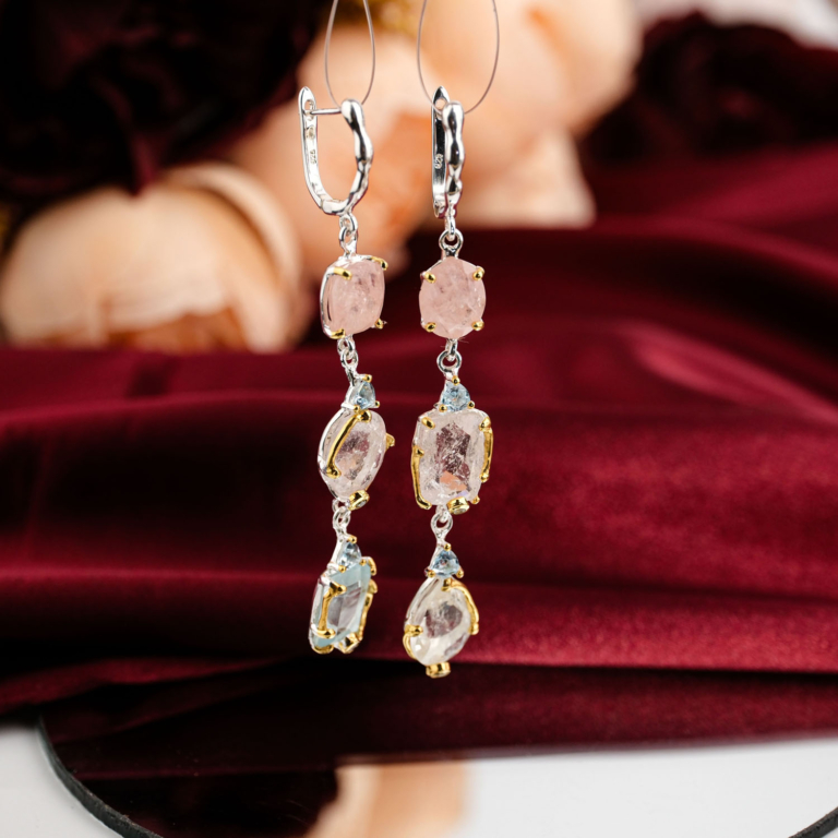 Boucles d'oreilles pendantes d'exception en argent 925 ornées de morganite rose pastel et topaze bleue sur fond rouge bordeaux.