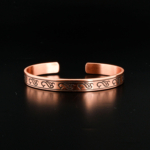 Bracelet jonc ouvert artisanal en cuivre pur avec gravures de vagues traditionnelles sur satin blanc.