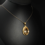 Collier pour femme avec pendentif ovale en citrine jaune naturelle et monture travaillée en argent 925 doré sur satin blanc