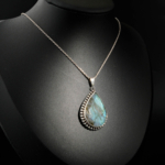 Collier fin pour femme avec pendentif goutte en labradorite naturelle facettée et chaîne argent 925 sur satin blanc.