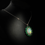 Collier médaillon raffiné pour femme en opale naturelle, émeraudes de Zambie et diamants en argent massif 925 sur satin blanc.