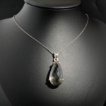 Collier fin pour femme avec pendentif goutte en quartz rutilé noir naturel facetté et argent 925 sur satin blanc.
