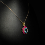 Collier fleur royal pour femme avec topaze bleue ovale naturelle et entourage rubis en argent 925 doré sur satin blanc.