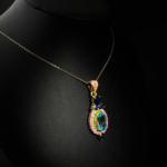 Collier médaillon royal pour femme avec topaze bleue naturelle, saphirs bleus, rubis et tsavorite en argent 925 plaqué or sur satin blanc.