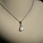 Damen Halskette aus 925 Silber mit facettiertem Tropfen Mondstein Anhänger auf dunklem Hintergrund.