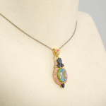 Damen Anhänger Kette aus 925 Silber vergoldet mit blauem Topas, Saphir, Rubin und Tsavorit Halo auf weißer Seide.