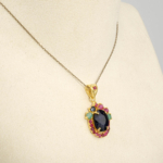 Damen Anhänger Kette aus 925 Silber vergoldet mit echtem ovalem blauem Saphir, Rubinen und Smaragden auf weißer Seide.