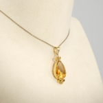 Damen Anhänger Kette aus 925 Silber vergoldet mit facettiertem Tropfen Citrin auf weißer Seide.