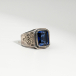 Herren Siegelring aus 925 Silber mit echtem blauem Saphir im Baguetteschliff und Vintage-Gravur auf weißer Seide.