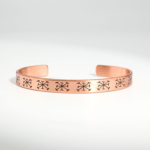 Podesiva narukvica od čistog bakra s ugraviranim geometrijskim simbolima na bijeloj svili.
