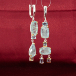 Genuine natural light blue aquamarine and blue topaz gemstone asymmetrical drop earrings 925 sterling silver light grey background.