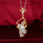 Hand carved natural aquamarine leaves cluster pendant with blue sapphire accents two tone 925 silver necklace red velvet background.