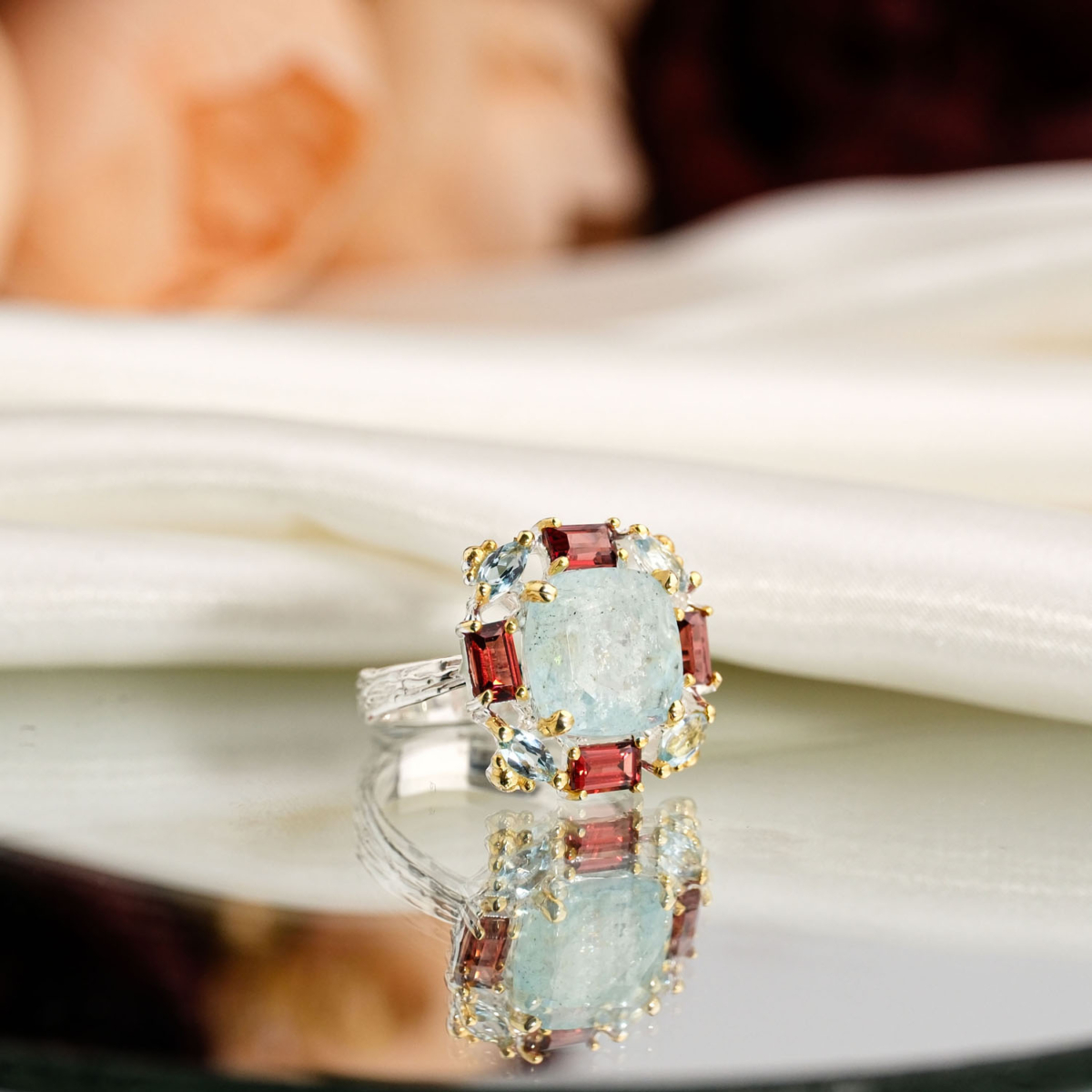 Natural light blue cushion cut aquamarine ring with baguette garnet halo in 925 sterling silver on white satin.
