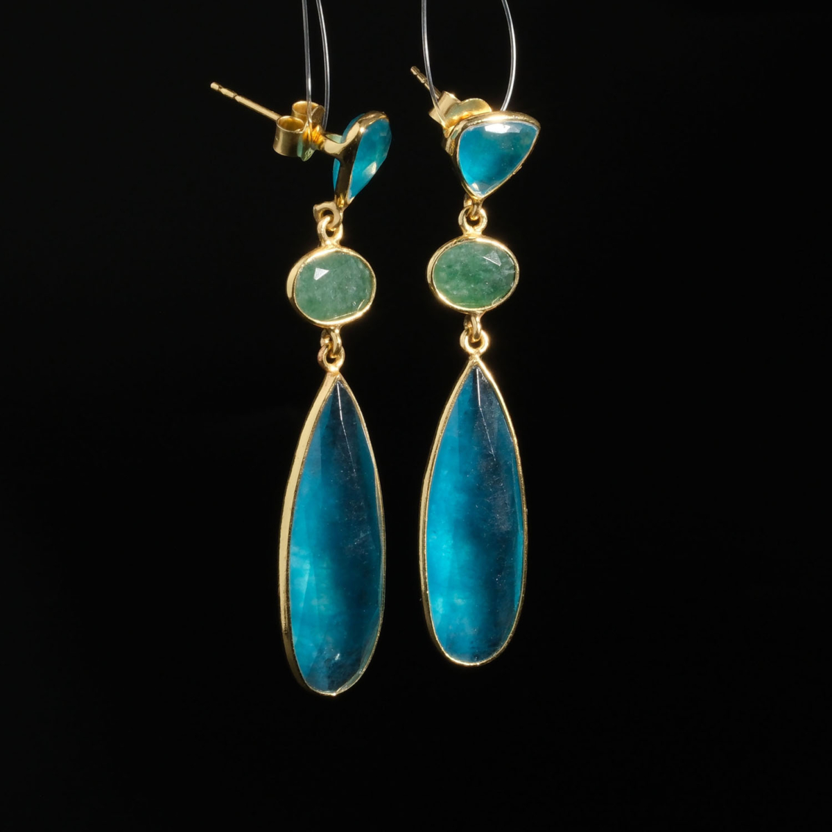 Genuine natural blue quartz and green emerald three tier dangle earrings yellow gold plated 925 sterling silver black background.
