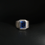 Natural 5.20 ct emerald cut blue sapphire signet ring with hand engraved details in 925 sterling silver on white satin.