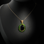 Natural faceted oval blue sapphire pendant necklace with green tsavorite halo in gold plated 925 silver on white satin.