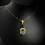 Natural faceted oval blue topaz pendant necklace with sapphire, ruby, and tsavorite halo in gold plated 925 silver on white satin.