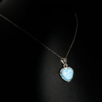 Genuine natural Caribbean blue larimar gemstone heart cabochon pendant 925 sterling silver chain black background.