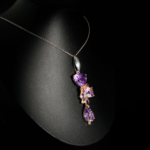 Genuine natural hand carved pear amethyst with pink tourmaline and blue topaz accents 925 sterling silver chain reflection.