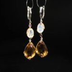 Natural faceted teardrop citrine, oval moonstone and amethyst dangle earrings in 925 sterling silver on white silk.
