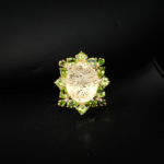 Natural light yellow faceted oval citrine statement ring haloed by peridot and tsavorite in gold-plated 925 silver on white satin.