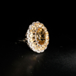 Natural faceted oval yellow citrine cocktail ring with double halo cluster in 925 sterling silver on white satin.