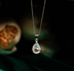 Natural faceted teardrop blue flash moonstone gemstone pendant necklace in 925 sterling silver on dark backdrop