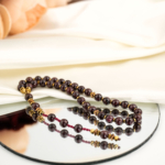 Genuine natural deep red garnet and golden hematite faceted bead 33 prayer beads tasbih black background.