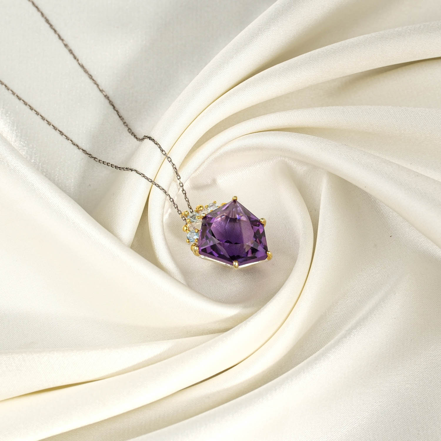 natural-geometric-amethyst-blue-topaz-two-tone-silver-necklace.jpg Beyaz saten kumaş üzerinde faset geometrik prizma mor ametist ve açık mavi topaz taşlı 925 ayar gümüş kadın kolye ucu ve zincir