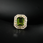 Natural emerald cut green tourmaline statement ring haloed by genuine diamonds in gold plated 925 silver on white silk.