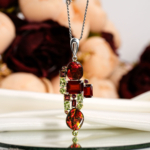 Genuine natural rainbow korite ammolite opal pendant with red garnet, pink tourmaline and green peridot 925 sterling silver black background.