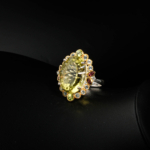 Natural faceted oval lemon quartz cocktail ring haloed by pink tourmaline, blue topaz and peridot in 925 silver on white satin