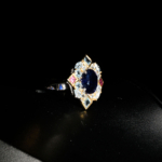 Natural oval blue sapphire ring with blue topaz and pink tourmaline geometric halo in 925 sterling silver on white satin.