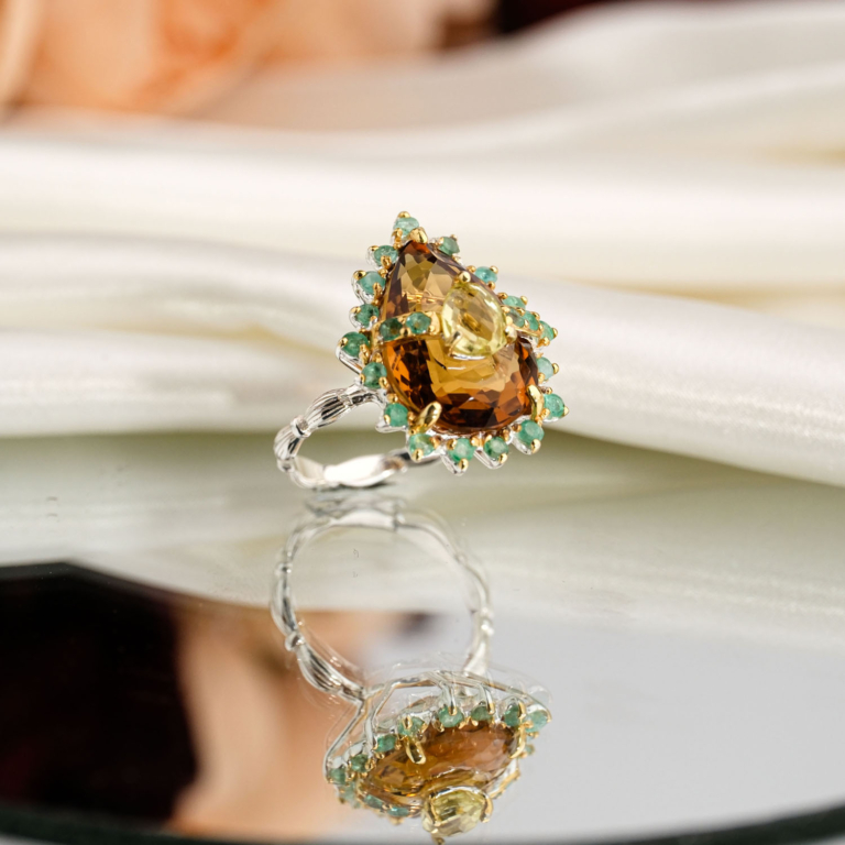 Natural teardrop honey citrine cocktail ring with green emerald halo in two-tone 925 sterling silver on white satin.