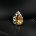 Natural pear shaped yellow citrine statement ring surrounded by blue topaz halo in rustic two-tone 925 silver on white silk