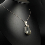 Natural faceted teardrop black tourmaline rutilated quartz gemstone pendant necklace in 925 sterling silver on white satin.