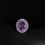 Genuine natural deep purple faceted oval amethyst gemstone ring surrounded by double halo cluster 925 sterling silver black background.