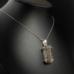 Natural faceted rectangular black tourmaline rutilated quartz gemstone pendant necklace in 925 sterling silver on white satin[