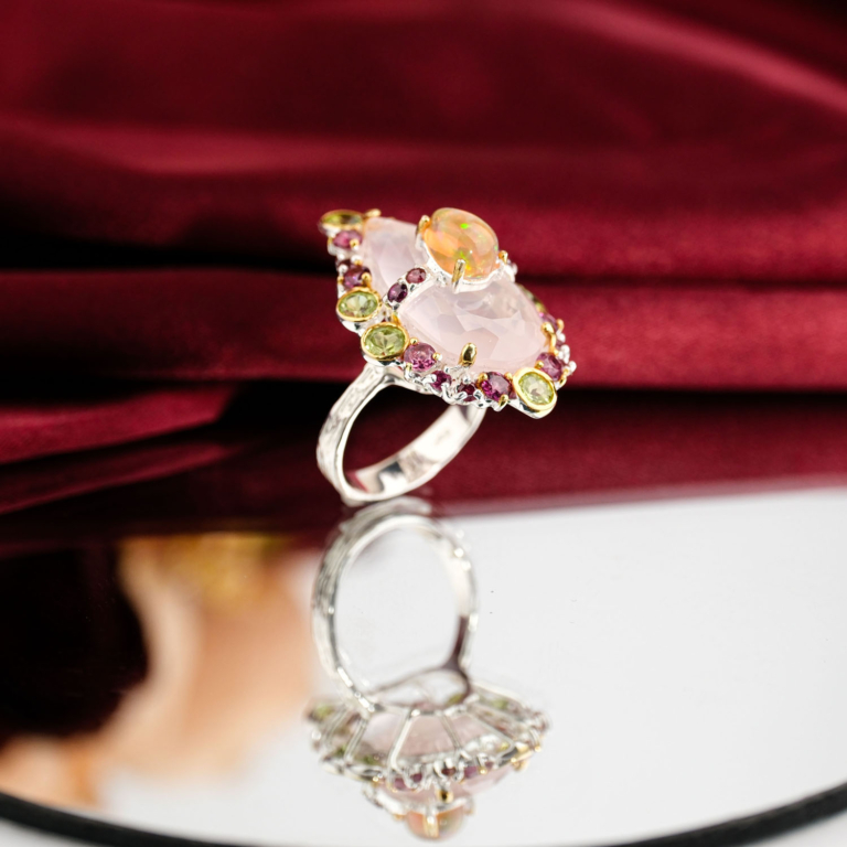 Natural faceted rose quartz statement ring with opal accent, peridot, and rubellite tourmaline halo in 925 silver on red velvet.