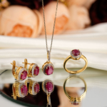 Natural faceted oval ruby and diamond halo jewelry set with necklace, earrings, and ring in gold plated 925 silver on white satin.