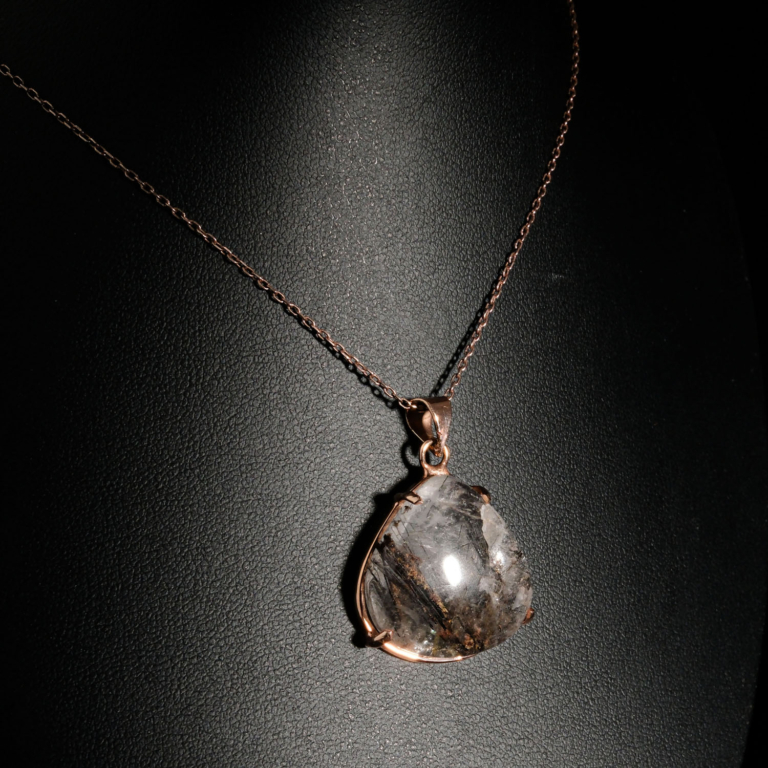 Genuine natural rutilated quartz triangular cabochon gemstone pendant rose gold plated 925 silver chain black background.
